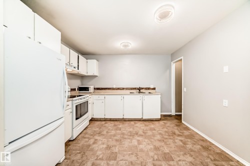 Kitchen featuring white appliances, white cabinets, and light countertops - 5308 20 Avenue, Edmonton, AB - Indoor Photo Showing Kitchen With Double Sink