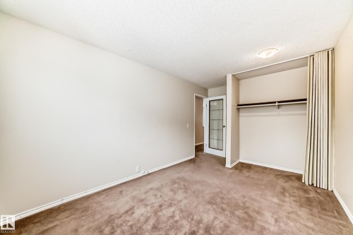 Unfurnished bedroom with a closet, carpet, and a textured ceiling - 5308 20 Avenue, Edmonton, AB - Indoor Photo Showing Other Room