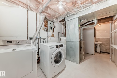 Laundry area with concrete flooring, washing machine and clothes dryer, electric panel, and water heater - 5308 20 Avenue, Edmonton, AB - Indoor Photo Showing Laundry Room