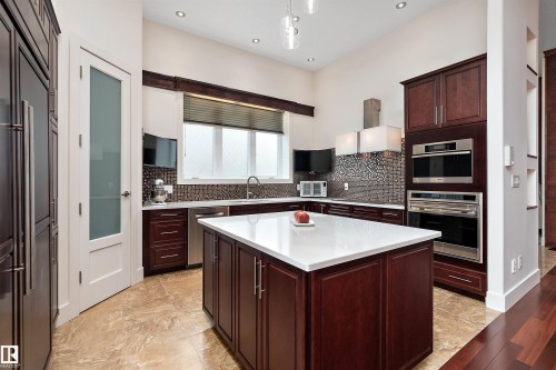 Kitchen with stainless steel appliances, range hood, a center island, tasteful backsplash, and dark wood finish cabinets - 169 Callaghan Drive, Edmonton, AB - Indoor Photo Showing Kitchen With Upgraded Kitchen