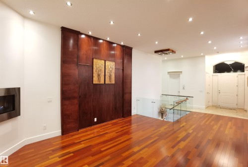 Unfurnished room with wood-type flooring, recessed lighting, and a glass covered fireplace - 169 Callaghan Drive, Edmonton, AB - Indoor Photo Showing Other Room