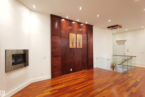Spare room featuring recessed lighting, wood finished floors, a glass covered fireplace, and a high ceiling - 169 Callaghan Drive, Edmonton, AB - Indoor Photo Showing Other Room