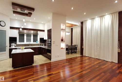 Kitchen with dark wood finish cabinets, light wood-type flooring, a center island, hanging light fixtures, and a high ceiling - 169 Callaghan Drive, Edmonton, AB - Indoor