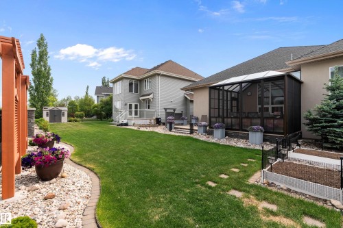View of grassy yard featuring a shed, a sunroom, a patio area, a vegetable garden, and a wooden deck - 169 Callaghan Drive, Edmonton, AB - Outdoor
