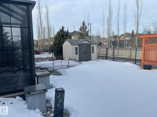 Yard layered in snow featuring a residential view, a fenced backyard, and a storage shed - 169 Callaghan Drive, Edmonton, AB - Outdoor