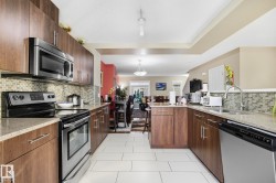 Kitchen with appliances with stainless steel finishes, tasteful backsplash, light stone counters, and a textured ceiling - 