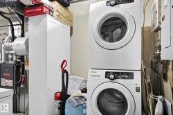 Washroom featuring stacked washer / drying machine and heating unit - 