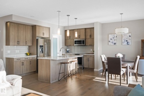 Kitchen with wood finish cabinetry, hanging light fixtures, a kitchen breakfast bar, and stainless steel appliances - 3904 5 Street, Edmonton, AB - Indoor