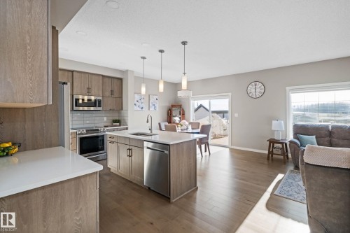 Kitchen with pendant lighting, tasteful backsplash, an island with sink, open floor plan, and stainless steel appliances - 3904 5 Street, Edmonton, AB - Indoor Photo Showing Kitchen