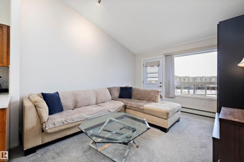 Living room with vaulted ceiling, baseboard heating, and carpet - 2407 320 Clareview Station Drive, Edmonton, AB - Indoor Photo Showing Living Room
