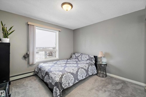Carpeted bedroom with a baseboard heating unit and a textured ceiling - 2407 320 Clareview Station Drive, Edmonton, AB - Indoor Photo Showing Bedroom