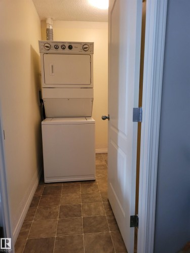 Dedicated laundry area featuring a stacked washer and dryer unit and tiled flooring - 2407 320 Clareview Station Drive, Edmonton, AB - Indoor Photo Showing Laundry Room