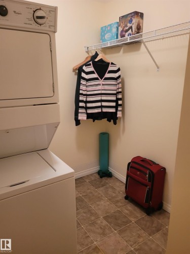 The property features a laundry area with a stacked washer and dryer, tiled flooring, and a wall-mounted wire shelf - 2407 320 Clareview Station Drive, Edmonton, AB - Indoor Photo Showing Laundry Room