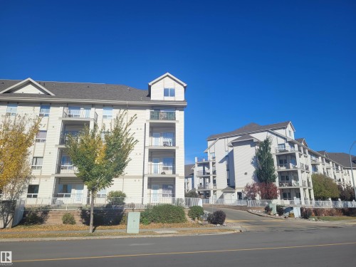 The property features multiple levels with balconies and a pitched roof design, situated amidst landscaped shrubbery and trees - 2407 320 Clareview Station Drive, Edmonton, AB - Outdoor With Facade