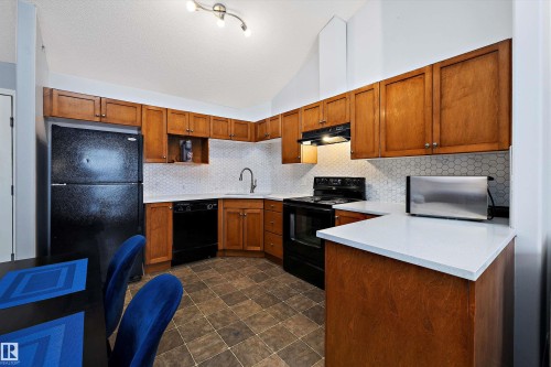Kitchen featuring black appliances, vaulted ceiling, wood finish cabinetry, decorative backsplash, and a peninsula - 2407 320 Clareview Station Drive, Edmonton, AB - Indoor Photo Showing Kitchen