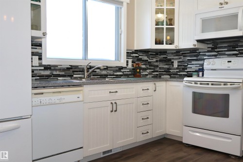 Kitchen with glass fronted cabinets, white appliances, white cabinets, and dark wood-style floors - 5220 - 56 Street, Barrhead, AB - Indoor Photo Showing Kitchen
