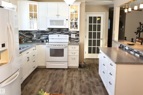 Kitchen featuring pendant lighting, white appliances, and white cabinets - 5220 - 56 Street, Barrhead, AB - Indoor Photo Showing Kitchen