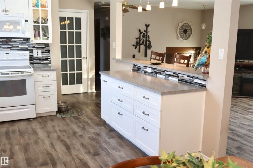 Kitchen featuring white cabinetry, white appliances, decorative backsplash, dark wood finished floors, and a ceiling fan - 5220 - 56 Street, Barrhead, AB - Indoor Photo Showing Kitchen