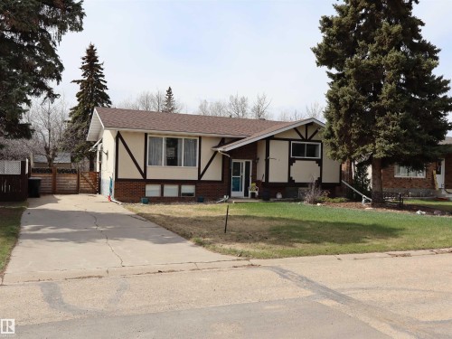 Split-level residence featuring a brown shingle roof, brick and stucco exterior, prominent dark trim detailing, a concrete driveway, and established front yard landscaping - 5220 - 56 Street, Barrhead, AB - Outdoor With Facade