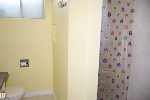 Full bath featuring a shower with shower curtain, vanity, and light tile patterned floors - 5220 - 56 Street, Barrhead, AB - Indoor Photo Showing Bathroom