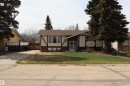 Bungalow-style residence featuring a two-tone facade with dark brick and cream paneling, a gabled roof, and a mature evergreen tree - 5220 - 56 Street, Barrhead, AB  - Outdoor 