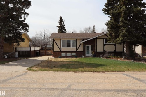 Exterior featuring a gabled roof, light-colored siding, dark trim, and a brick foundation - 5220 - 56 Street, Barrhead, AB - Outdoor