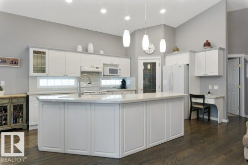 Kitchen with a spacious island, hanging light fixtures, dark wood finished floors, white cabinets, and lofted ceiling - 8 Osborne Close, St. Albert, AB - Indoor Photo Showing Kitchen With Upgraded Kitchen