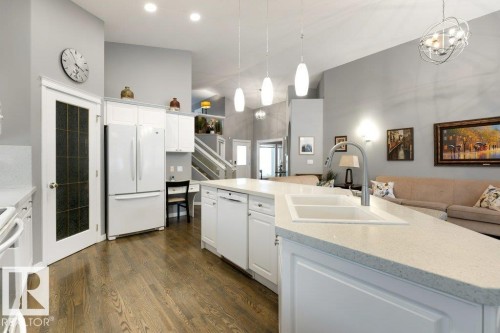 Kitchen featuring white appliances, white cabinets, open floor plan, dark wood-style flooring, and a high ceiling - 8 Osborne Close, St. Albert, AB - Indoor Photo Showing Kitchen With Double Sink