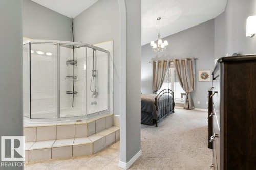 Ensuite bathroom featuring a shower stall, light colored carpet, lofted ceiling, and a chandelier - 8 Osborne Close, St. Albert, AB - Indoor
