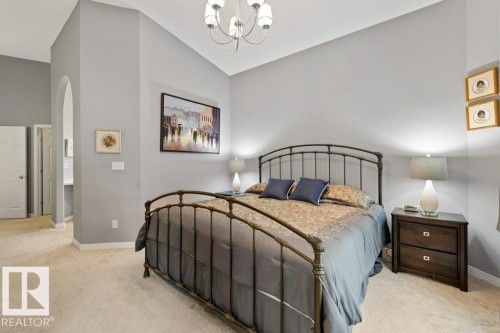 Carpeted bedroom with arched walkways, hanging lights, and lofted ceiling - 8 Osborne Close, St. Albert, AB - Indoor Photo Showing Bedroom