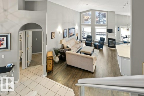 Living room with hanging lights, vaulted ceiling, arched walkways, a glass covered fireplace, and light tile patterned floors - 8 Osborne Close, St. Albert, AB - Indoor Photo Showing Living Room