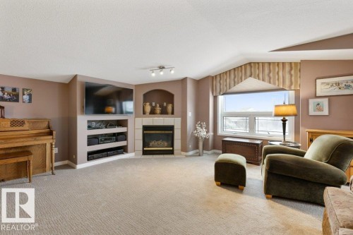 Living room featuring a tiled fireplace, carpet, and built in shelves - 8 Osborne Close, St. Albert, AB - Indoor Photo Showing Living Room With Fireplace