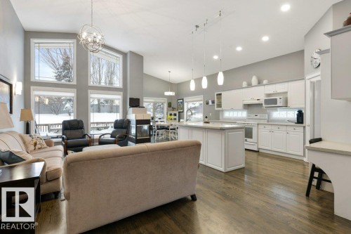 Living area featuring dark wood-style floors, suspended lighting, and lofted ceiling - 8 Osborne Close, St. Albert, AB - Indoor