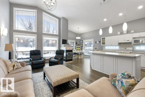 Living area with dark wood-style floors, lofted ceiling, and hanging lights - 8 Osborne Close, St. Albert, AB - Indoor Photo Showing Living Room