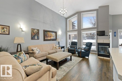 Living room with dark wood finished floors, a glass covered fireplace, hanging lights, and vaulted ceiling - 8 Osborne Close, St. Albert, AB - Indoor Photo Showing Living Room