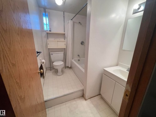 Full bath with vanity, shower / bath combo with shower curtain, and light tile patterned floors - 11250 72 Avenue, Edmonton, AB - Indoor Photo Showing Bathroom