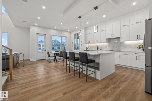 Kitchen featuring a center island, a breakfast bar, white cabinets, backsplash, and hanging light fixtures - 132 Edgewater Circle, Leduc, AB - Indoor Photo Showing Kitchen With Upgraded Kitchen