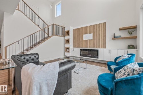 Living room featuring a glass covered fireplace, a high ceiling, and wood finished floors - 132 Edgewater Circle, Leduc, AB - Indoor Photo Showing Other Room With Fireplace