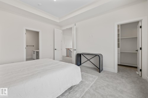 Bedroom featuring a spacious closet, light colored carpet, ensuite bath, and a raised ceiling - 132 Edgewater Circle, Leduc, AB - Indoor Photo Showing Bedroom