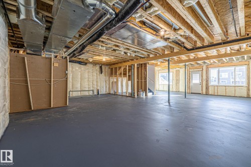 The unfinished space features exposed wood framing and ceiling beams, a painted concrete floor, and insulated walls - 132 Edgewater Circle, Leduc, AB - Indoor Photo Showing Basement