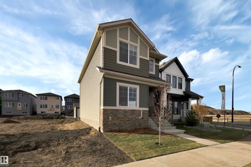 View of front facade featuring stone siding, a residential view, and a front lawn - 2275 Alces Drive, Edmonton, AB - Outdoor With Facade