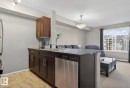 Kitchen with stainless steel dishwasher, open floor plan, a peninsula, hanging light fixtures, and a textured ceiling - 310 18122 77 Street, Edmonton, AB  - Indoor Photo Showing Kitchen With Double Sink 