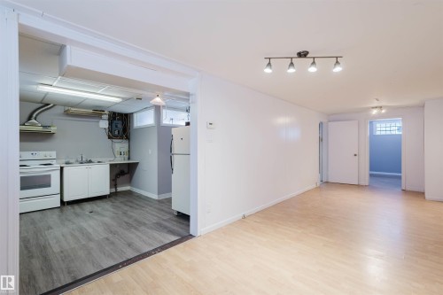 Kitchen featuring white appliances, light wood-style floors, light countertops, white cabinetry, and extractor fan - 6048 105B Street Nw, Edmonton, AB - Indoor Photo Showing Kitchen