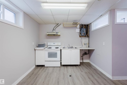 Kitchen with a drop ceiling, plenty of natural light, white electric range oven, white cabinets, and light countertops - 6048 105B Street Nw, Edmonton, AB - Indoor Photo Showing Kitchen With Double Sink
