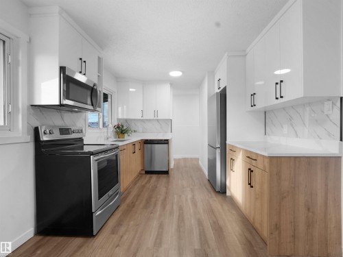 Kitchen featuring stainless steel appliances, dual tone cabinets, modern cabinets, and light wood-style floors - 10329 132 Avenue, Edmonton, AB - Indoor Photo Showing Kitchen