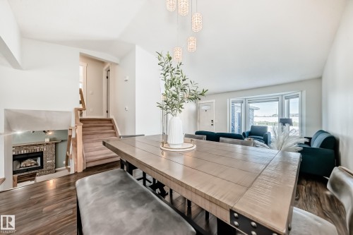 Dining room featuring dark wood-style flooring, a fireplace, and vaulted ceiling - 7011 190B Street, Edmonton, AB - Indoor With Fireplace