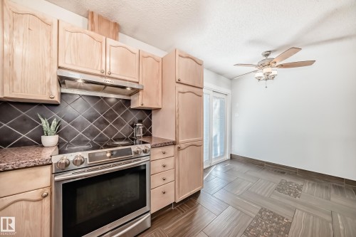 Kitchen with light wood finish cabinets, stainless steel range with electric stovetop, ceiling fan, and a textured ceiling - 7011 190B Street, Edmonton, AB - Indoor Photo Showing Kitchen