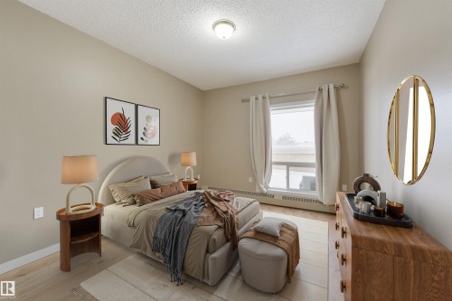 Bedroom featuring light wood finished floors, a textured ceiling, and baseboard heating - 232 15499 Castle Downs Road, Edmonton, AB - Indoor Photo Showing Bedroom