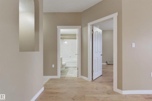 Corridor with light wood-style floors, a textured ceiling, and a baseboard radiator - 232 15499 Castle Downs Road, Edmonton, AB - Indoor Photo Showing Other Room
