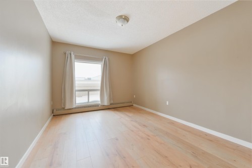 Spare room with a baseboard heating unit, light wood-type flooring, and a textured ceiling - 232 15499 Castle Downs Road, Edmonton, AB - Indoor Photo Showing Other Room